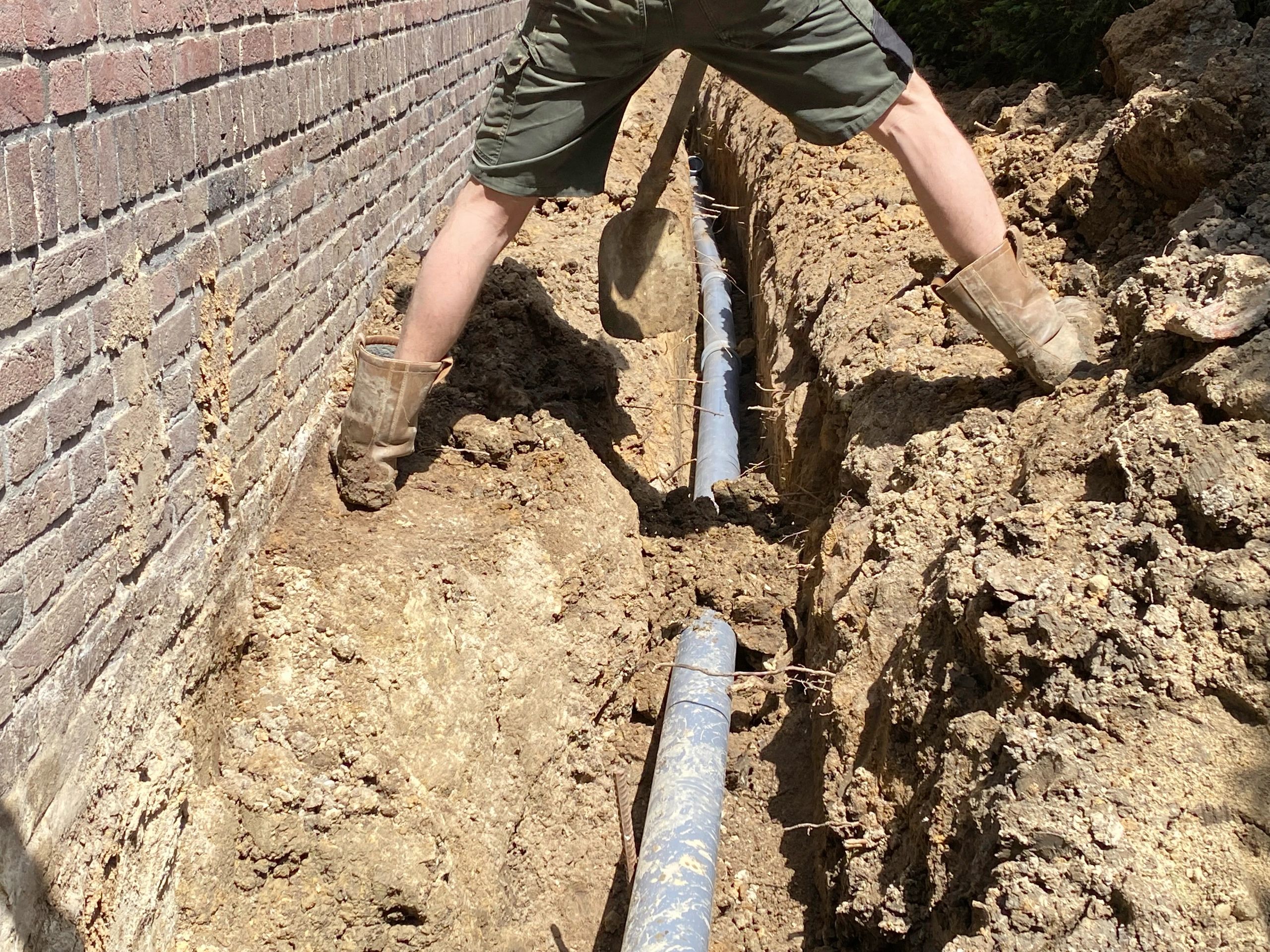 Construction worker excavating drainage trench